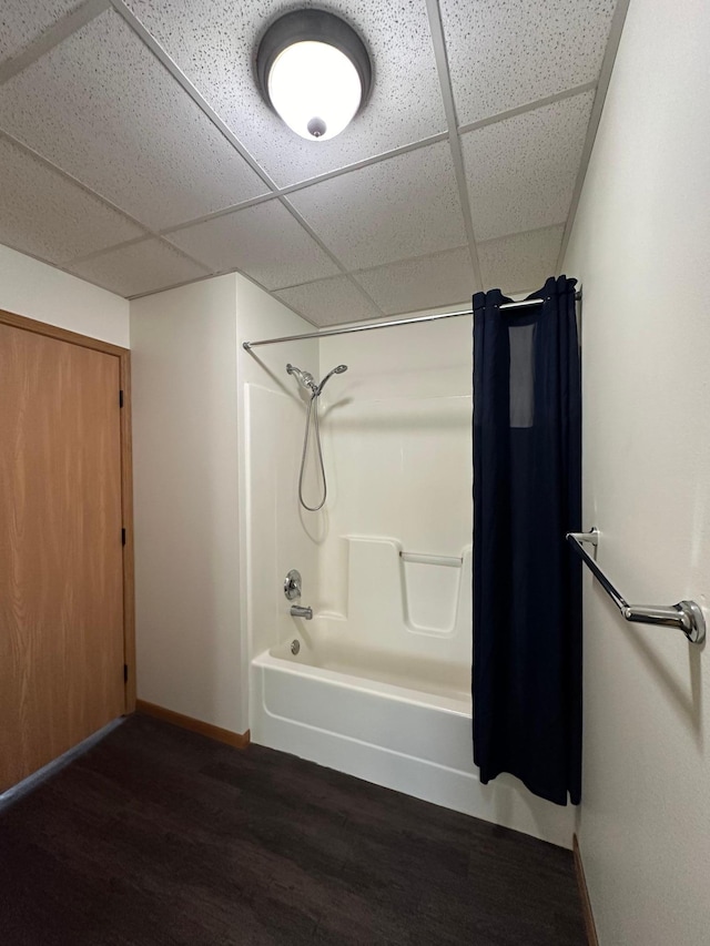 bathroom featuring hardwood / wood-style floors, a paneled ceiling, and shower / bathtub combination with curtain