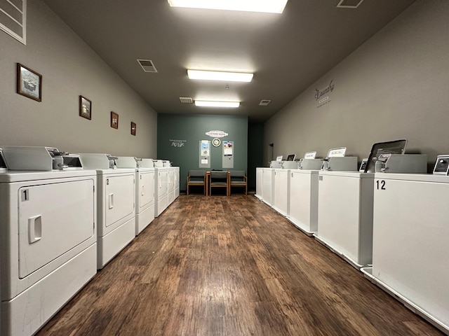 clothes washing area with washer and dryer and dark wood-type flooring