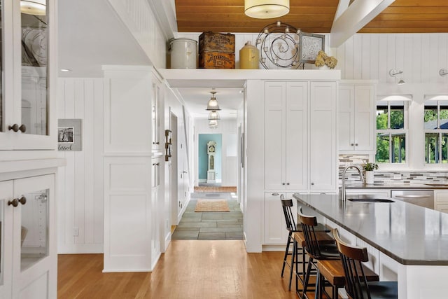 kitchen with a center island, white cabinets, light wood-type flooring, wooden ceiling, and sink