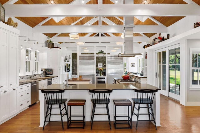 kitchen featuring lofted ceiling with beams, white cabinetry, stainless steel appliances, and wood ceiling