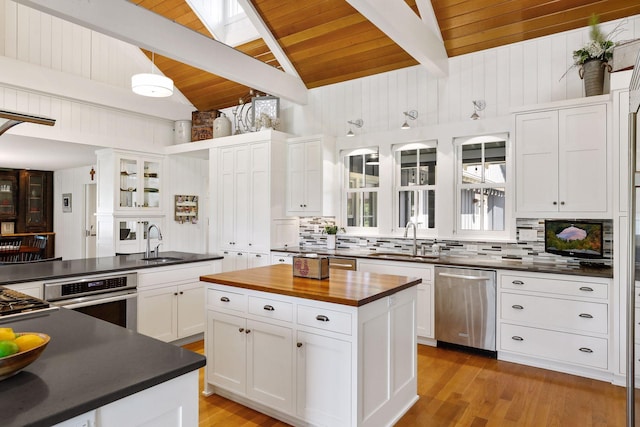 kitchen featuring lofted ceiling with beams, sink, light wood-type flooring, stainless steel appliances, and wooden ceiling