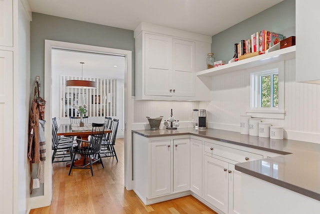 kitchen featuring white cabinets, hanging light fixtures, and light wood-type flooring