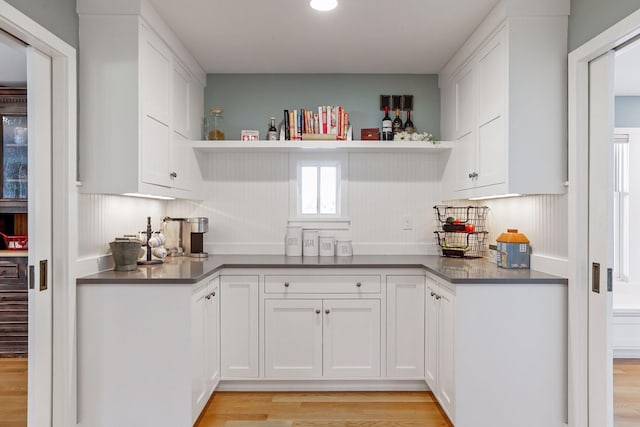 kitchen featuring backsplash, light hardwood / wood-style floors, and white cabinets