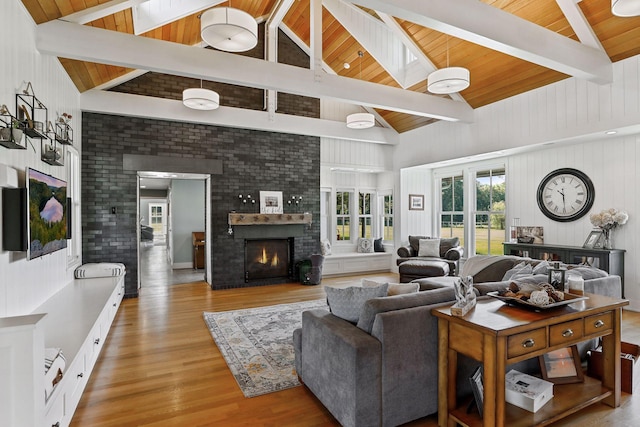 living room featuring a skylight, a brick fireplace, light hardwood / wood-style floors, beam ceiling, and wooden ceiling