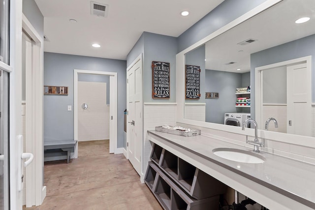 bathroom featuring concrete flooring, vanity with extensive cabinet space, and washing machine and clothes dryer