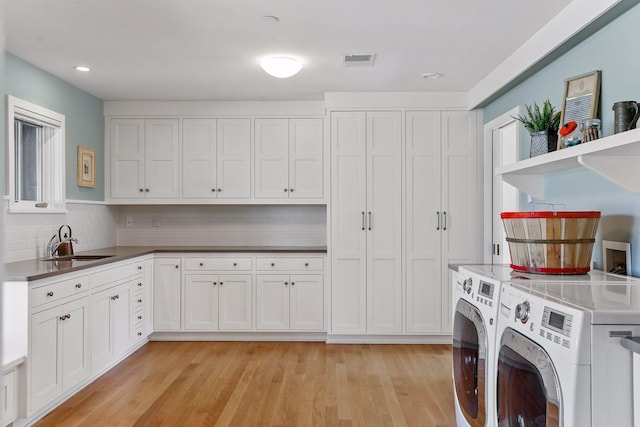 washroom with sink, independent washer and dryer, light wood-type flooring, and cabinets