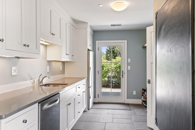 kitchen with sink, light tile floors, stainless steel appliances, and white cabinetry