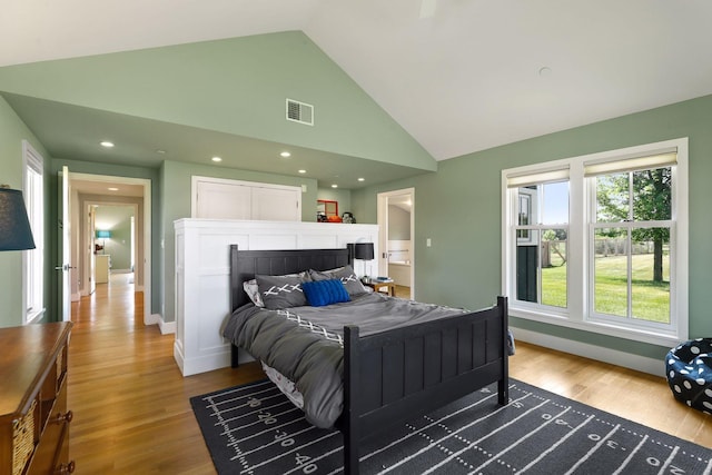 bedroom with wood-type flooring, high vaulted ceiling, and a fireplace