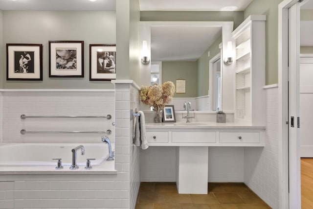 bathroom featuring a relaxing tiled bath, tile floors, and sink