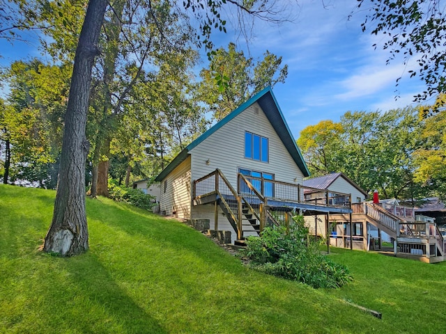 rear view of house featuring a wooden deck and a yard