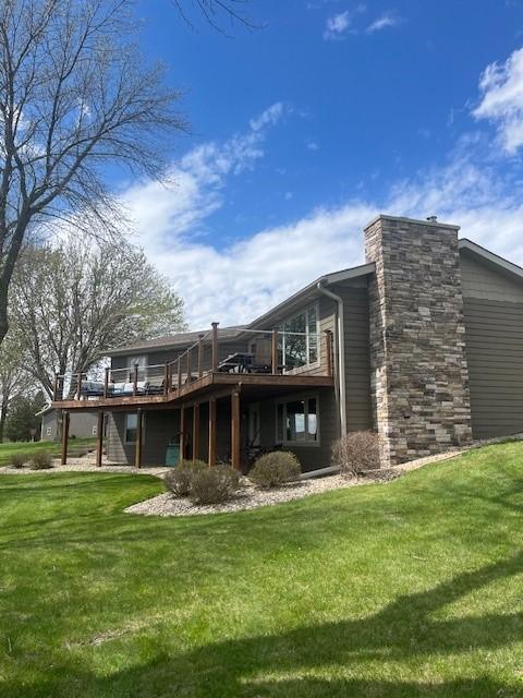 back of property with a deck and a lawn