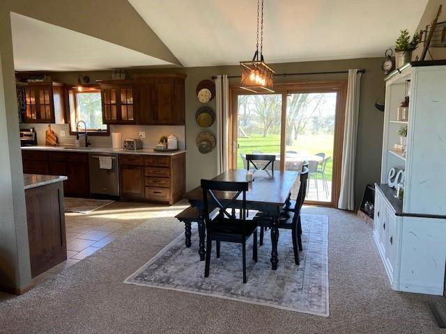 tiled dining space with sink and vaulted ceiling