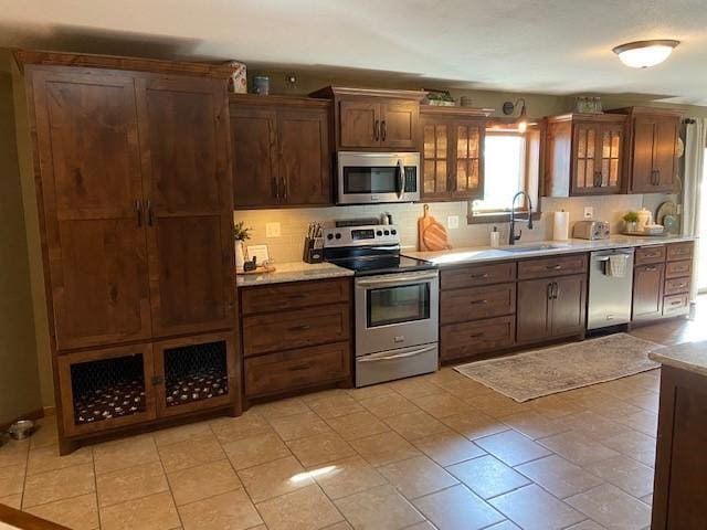 kitchen featuring stainless steel appliances, sink, and light tile flooring