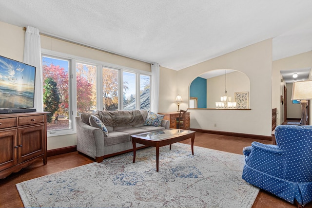 living room featuring vaulted ceiling, dark hardwood / wood-style flooring, a textured ceiling, and a chandelier