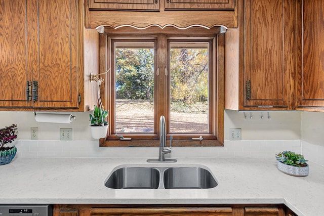 kitchen with dishwasher, light stone counters, sink, and a wealth of natural light