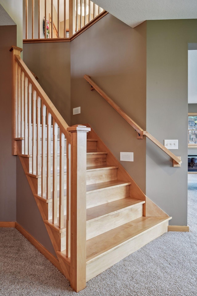 stairs with a textured ceiling, carpet flooring, and a wealth of natural light