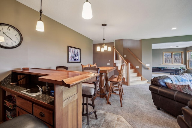 kitchen featuring light carpet, pendant lighting, a notable chandelier, and vaulted ceiling