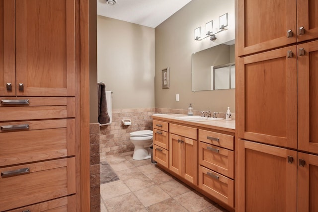 bathroom with vanity, tile walls, and toilet