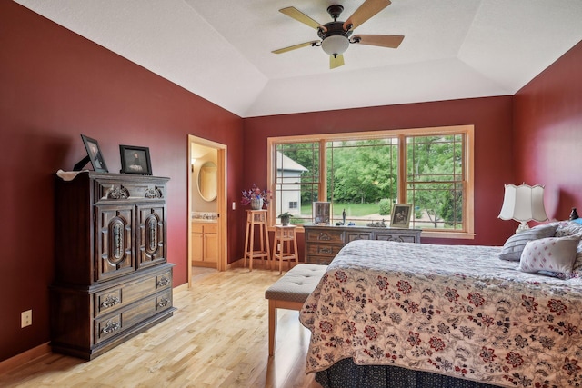 bedroom with ceiling fan, light wood-type flooring, ensuite bath, and vaulted ceiling