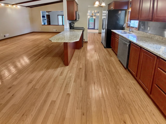 kitchen with a kitchen bar, appliances with stainless steel finishes, sink, light hardwood / wood-style flooring, and a notable chandelier