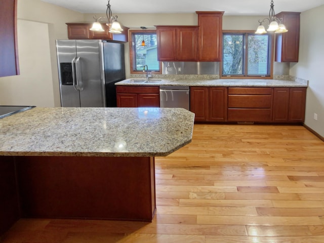 kitchen with appliances with stainless steel finishes, light hardwood / wood-style flooring, and a notable chandelier