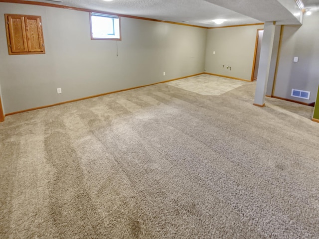 basement featuring a textured ceiling, ornamental molding, and light carpet