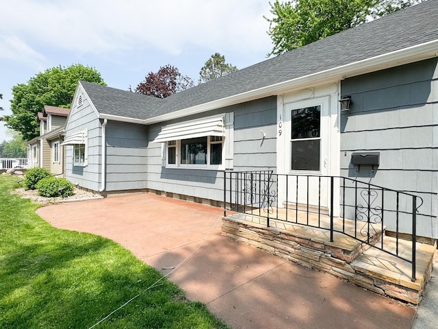 view of exterior entry featuring a lawn and a patio