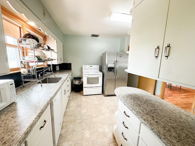 kitchen with white cabinetry, light stone countertops, sink, and white appliances