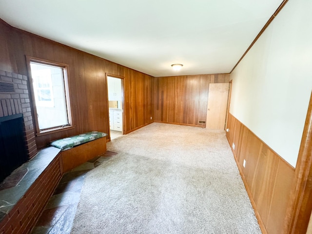 carpeted spare room with a brick fireplace