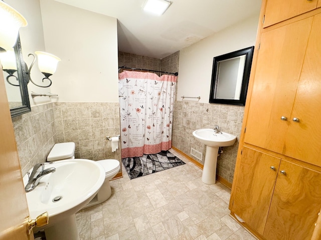 bathroom featuring tile walls, sink, a shower with curtain, and toilet