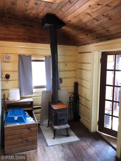 interior space with a wood stove, wood walls, dark hardwood / wood-style flooring, and wooden ceiling