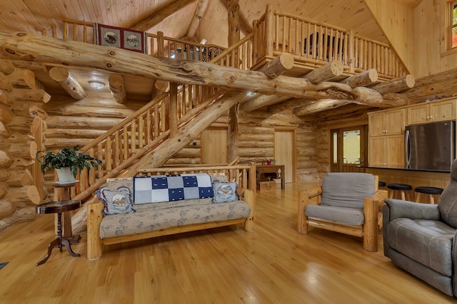 living room featuring light hardwood / wood-style floors, log walls, and high vaulted ceiling