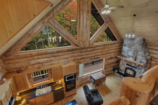 living room with a fireplace, high vaulted ceiling, sink, light hardwood / wood-style floors, and rustic walls