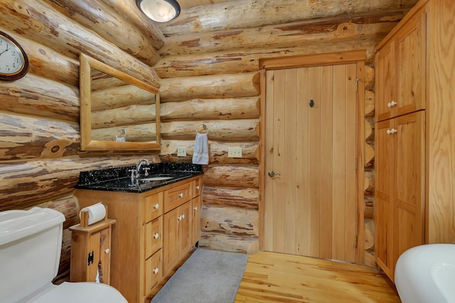 bathroom with vanity, hardwood / wood-style flooring, toilet, and rustic walls