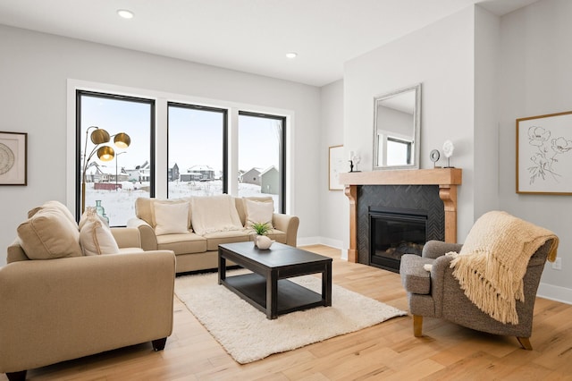 living room with light wood-type flooring, a wealth of natural light, and a tiled fireplace