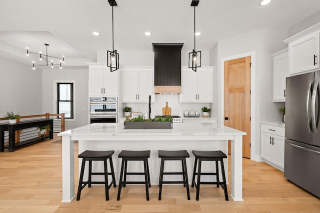 kitchen featuring appliances with stainless steel finishes, light hardwood / wood-style floors, and decorative light fixtures