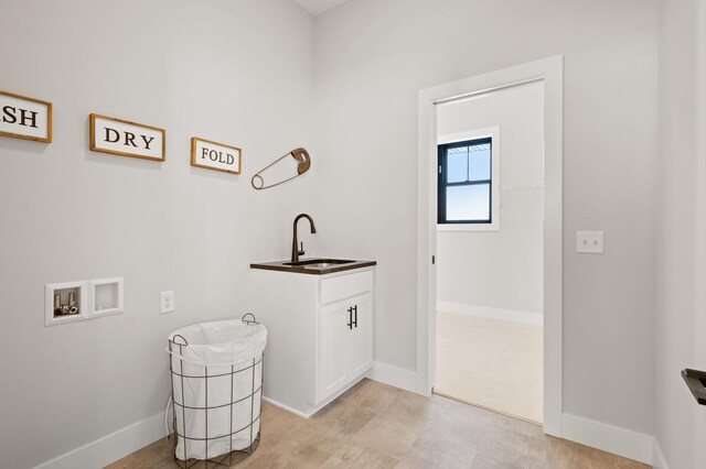 laundry area with light colored carpet, cabinets, sink, and washer hookup