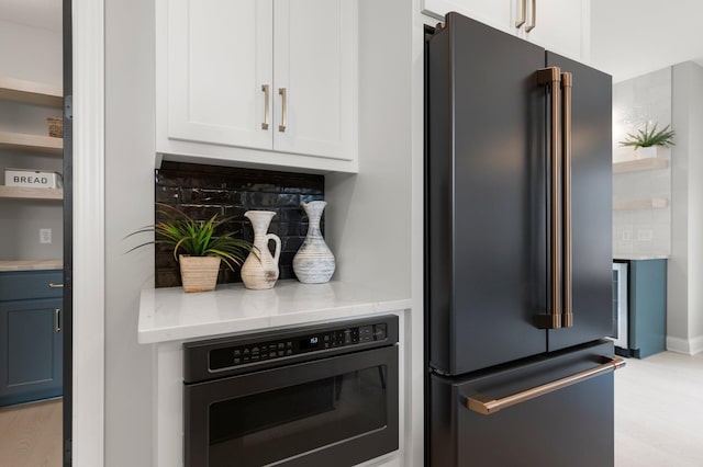 kitchen featuring oven, light hardwood / wood-style floors, high end fridge, and tasteful backsplash