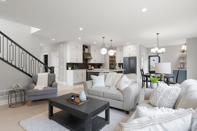 living room featuring sink, light wood-type flooring, and an inviting chandelier