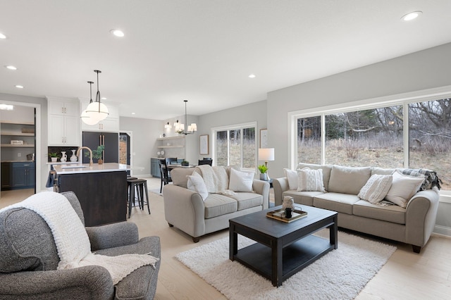 living room with light hardwood / wood-style flooring, sink, and an inviting chandelier