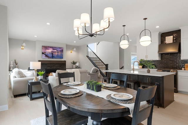 dining room with an inviting chandelier, a brick fireplace, and light wood-type flooring