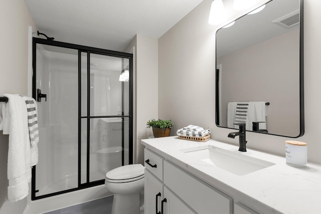 bathroom featuring a shower with door, vanity, and toilet