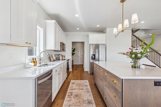 kitchen featuring sink, appliances with stainless steel finishes, hanging light fixtures, a center island, and white cabinets