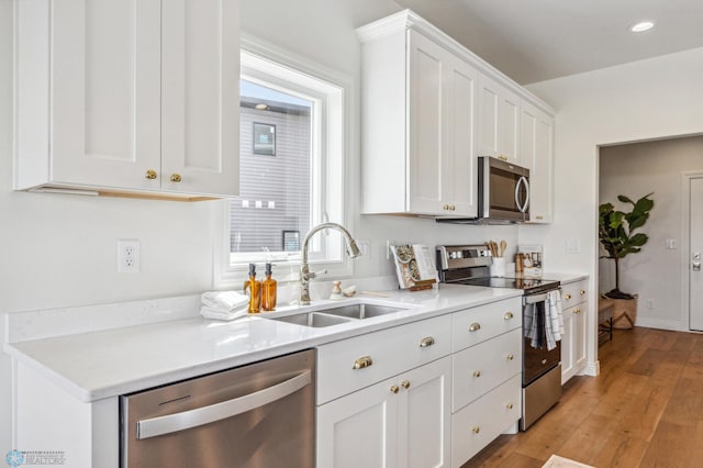 kitchen featuring appliances with stainless steel finishes, light hardwood / wood-style floors, sink, and white cabinets