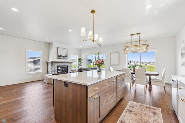 kitchen featuring a center island, dark wood-type flooring, pendant lighting, and a stone fireplace