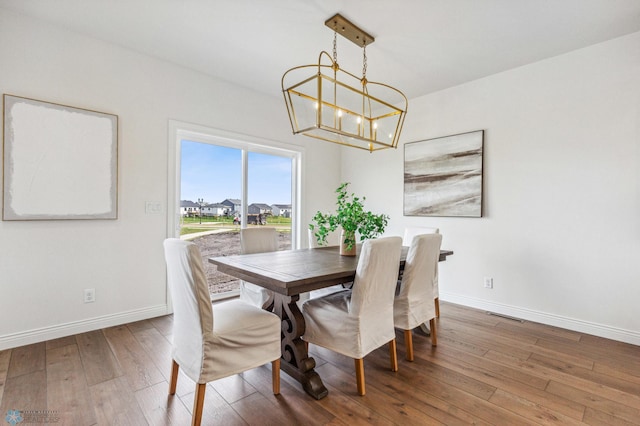 dining space featuring hardwood / wood-style flooring and a chandelier