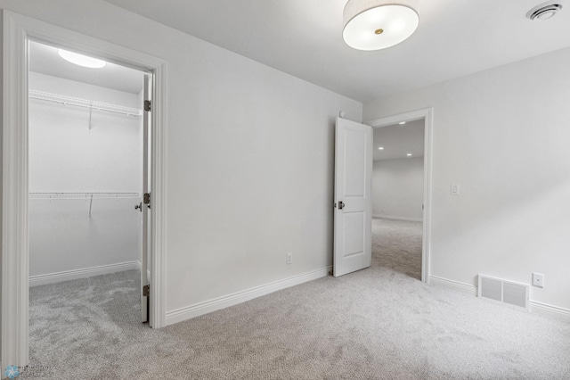 unfurnished bedroom featuring light carpet and a closet