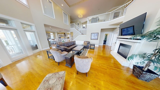 living room with light hardwood / wood-style floors, a wealth of natural light, a high end fireplace, and a high ceiling