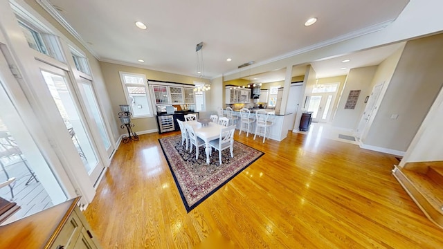 dining space with ornamental molding and light hardwood / wood-style flooring