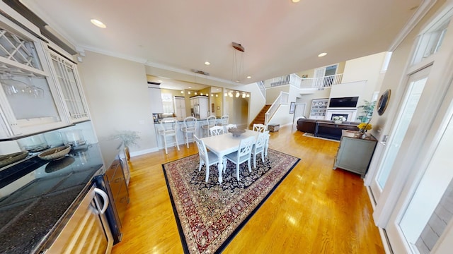 dining room featuring a healthy amount of sunlight, light wood-type flooring, and ornamental molding